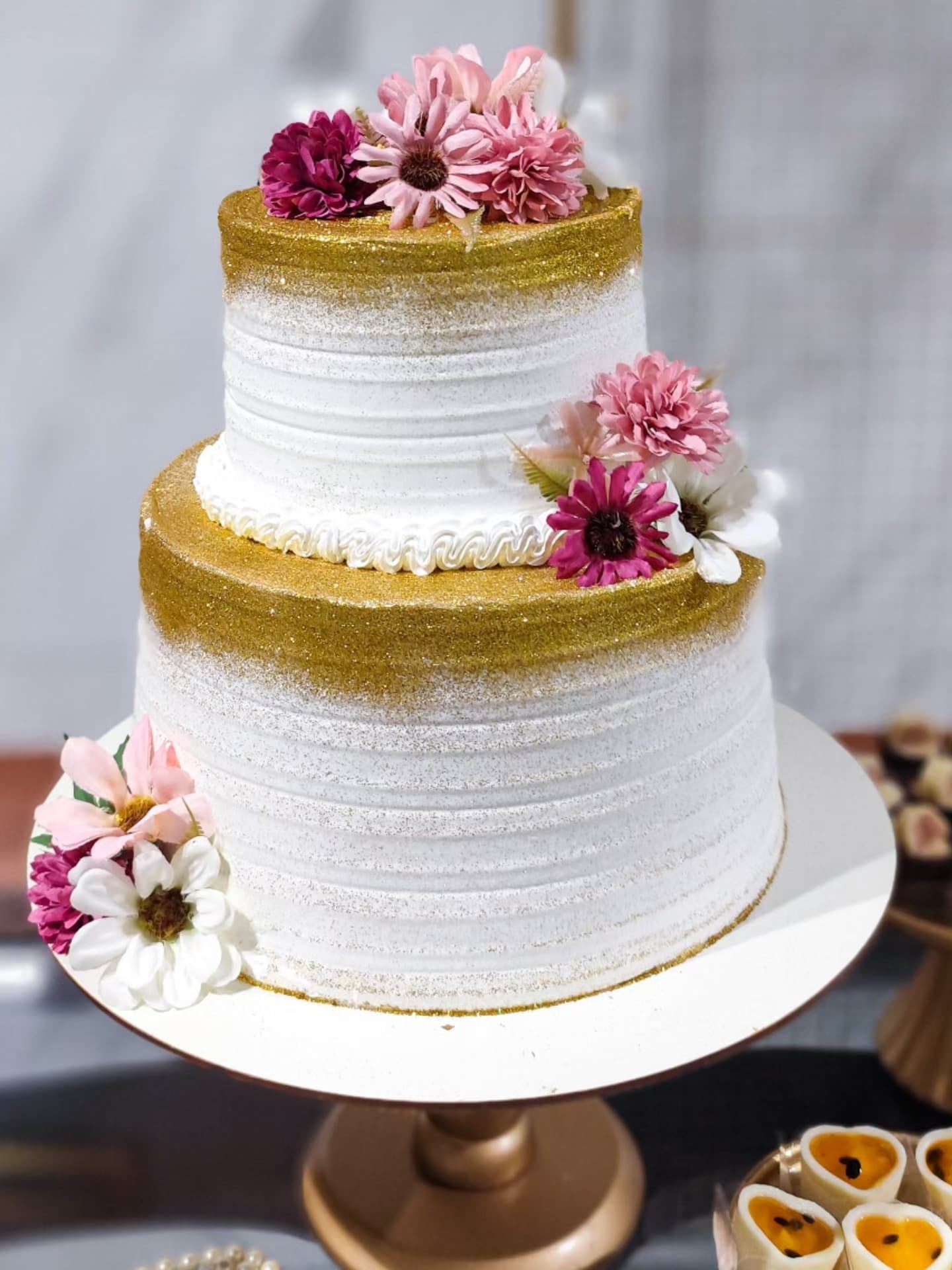 Bolo de dois andares branco e dourado com flores cor-de-rosa feito pela Deliciê